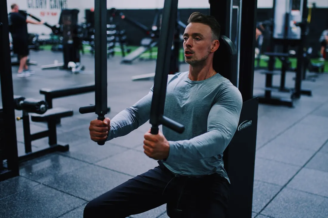 Athlete training on a cable machine in a gym between recovery sessions
