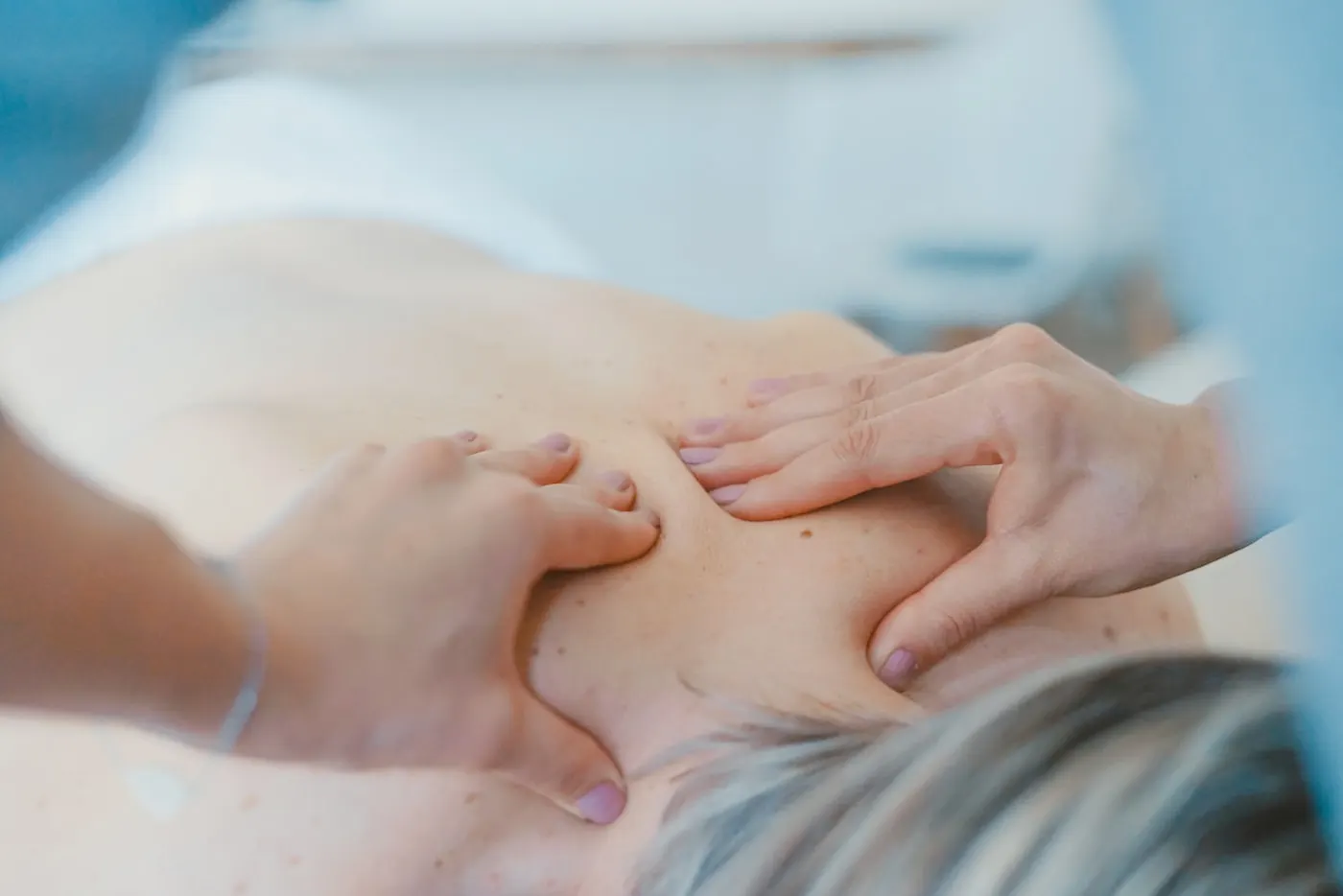 Massage therapist applying focused thumb pressure to trigger points in a client's neck and shoulders