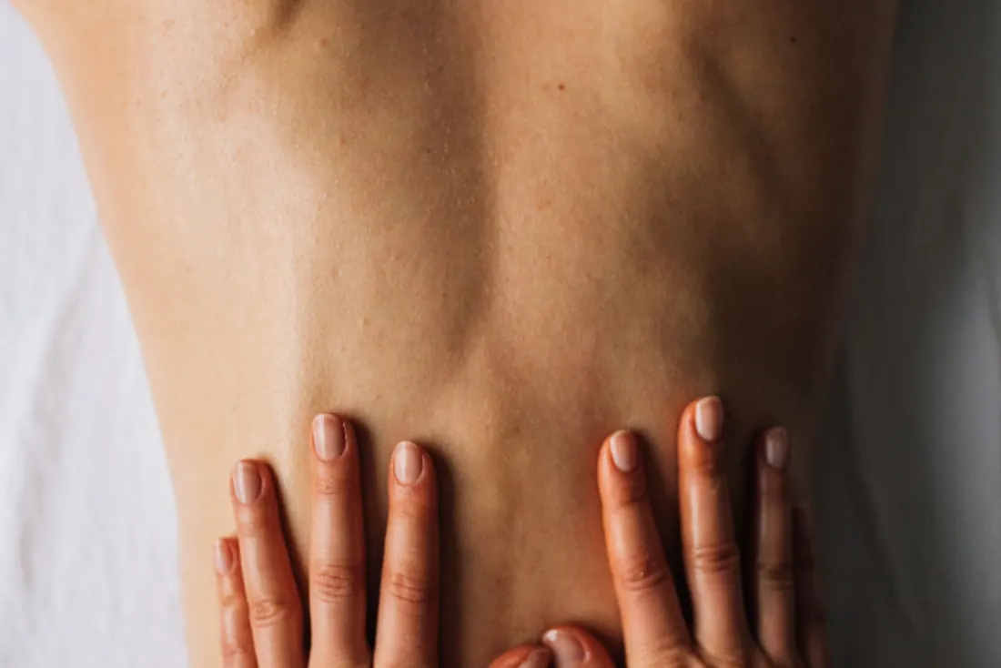 Therapist's hands applying massage strokes to a client's back
